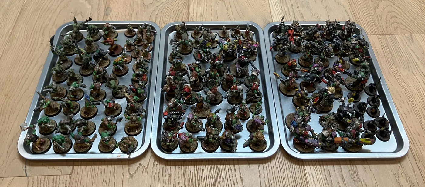 A collection of painted Ork tabletop miniatures arranged on three trays